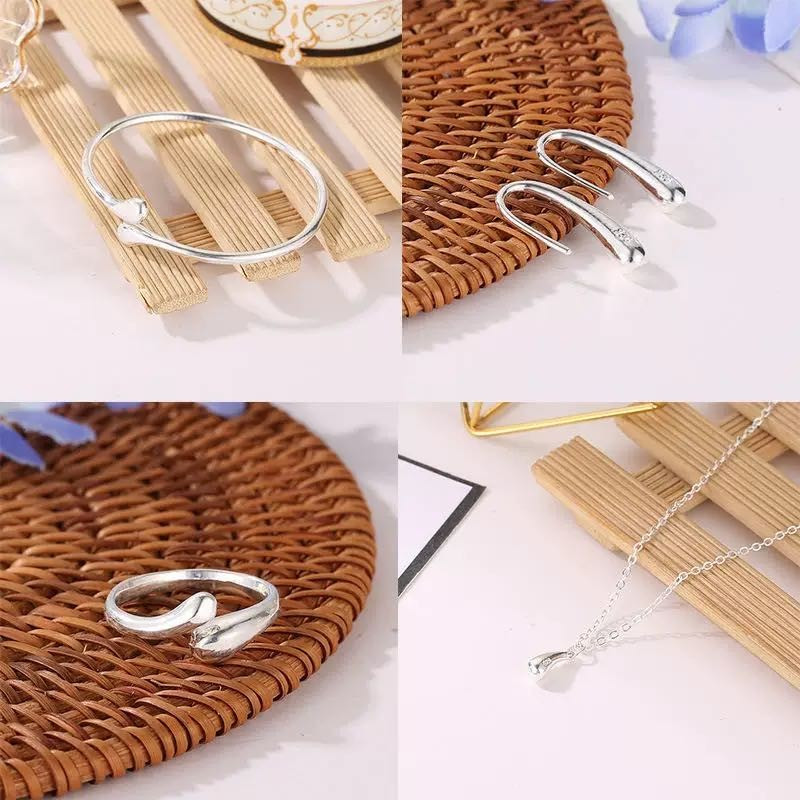 Conjunto de joias em formato de gota, composto por quatro peças em ouro ou prata: brincos, colar, pulseira e anel.