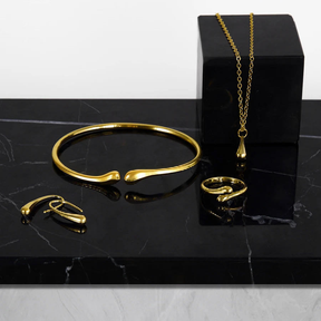 Conjunto de joias em formato de gota, composto por quatro peças em ouro ou prata: brincos, colar, pulseira e anel.