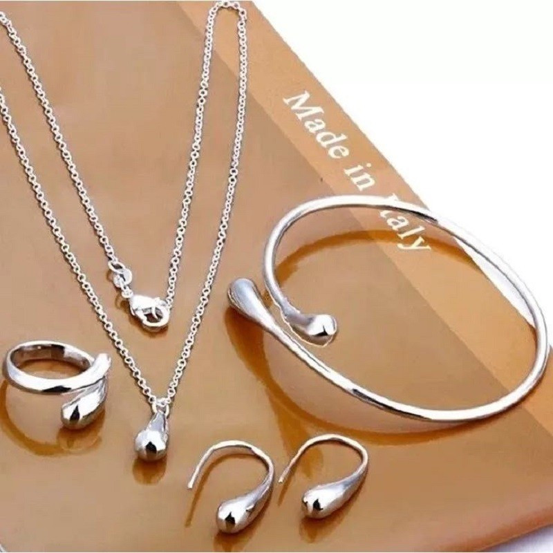 Conjunto de joias em formato de gota, composto por quatro peças em ouro ou prata: brincos, colar, pulseira e anel.